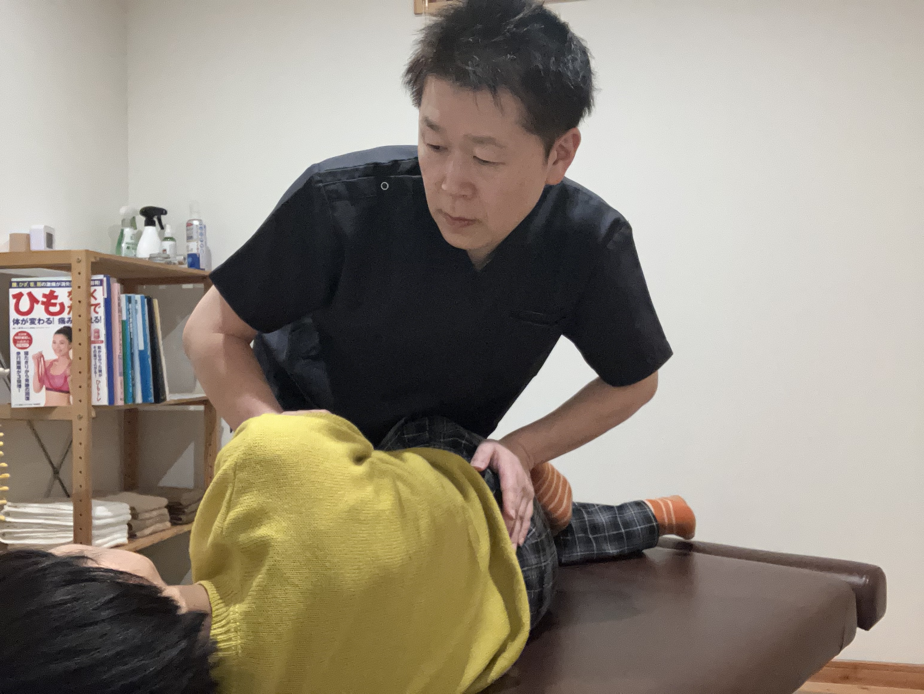 「北見のサインカイロ整体院の院長による施術風景。患者の腰または骨盤周りに手を当てて行う、ソフトで安全なカイロプラクティック（整体）の施術。」